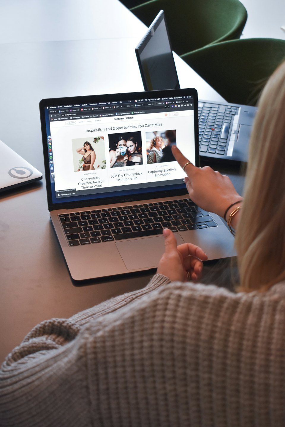 Osoba ukazuje na web Cherrydeck na MacBooku v kanceláři.