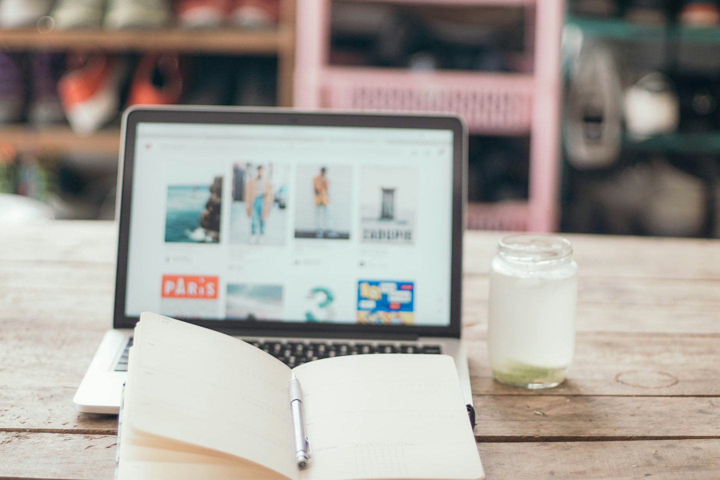 Notebook zobrazující web e-shopu na dřevěném stole.